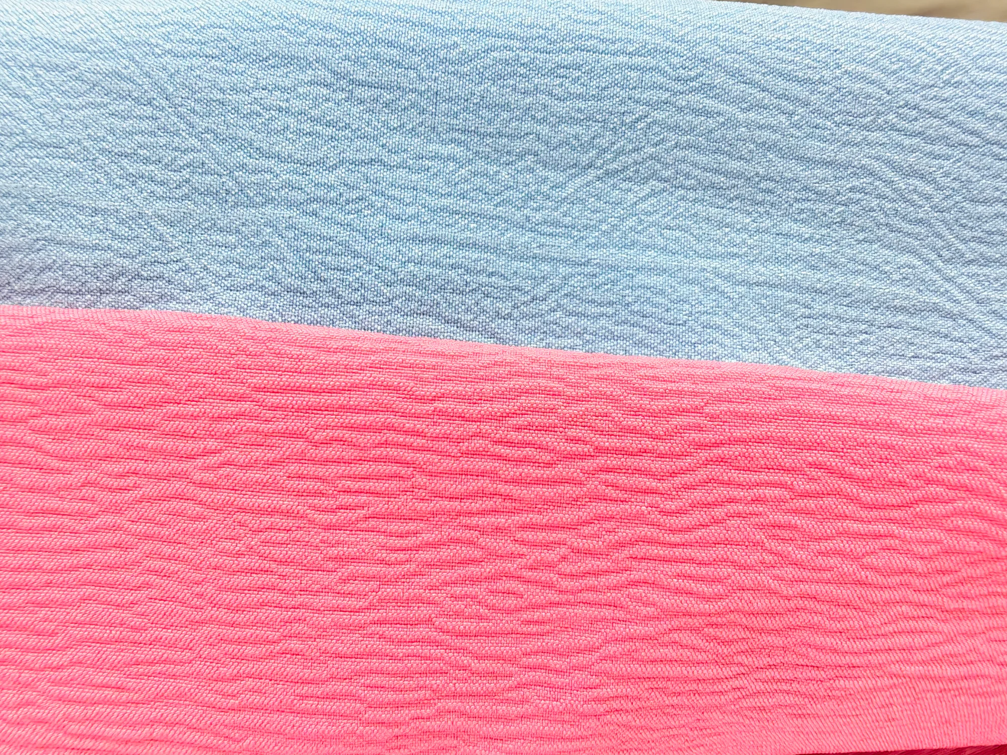 Sky-blue organic crinkle and pink ant-crepe swatches made from the same 100D four-way stretch crepe greige fabric.