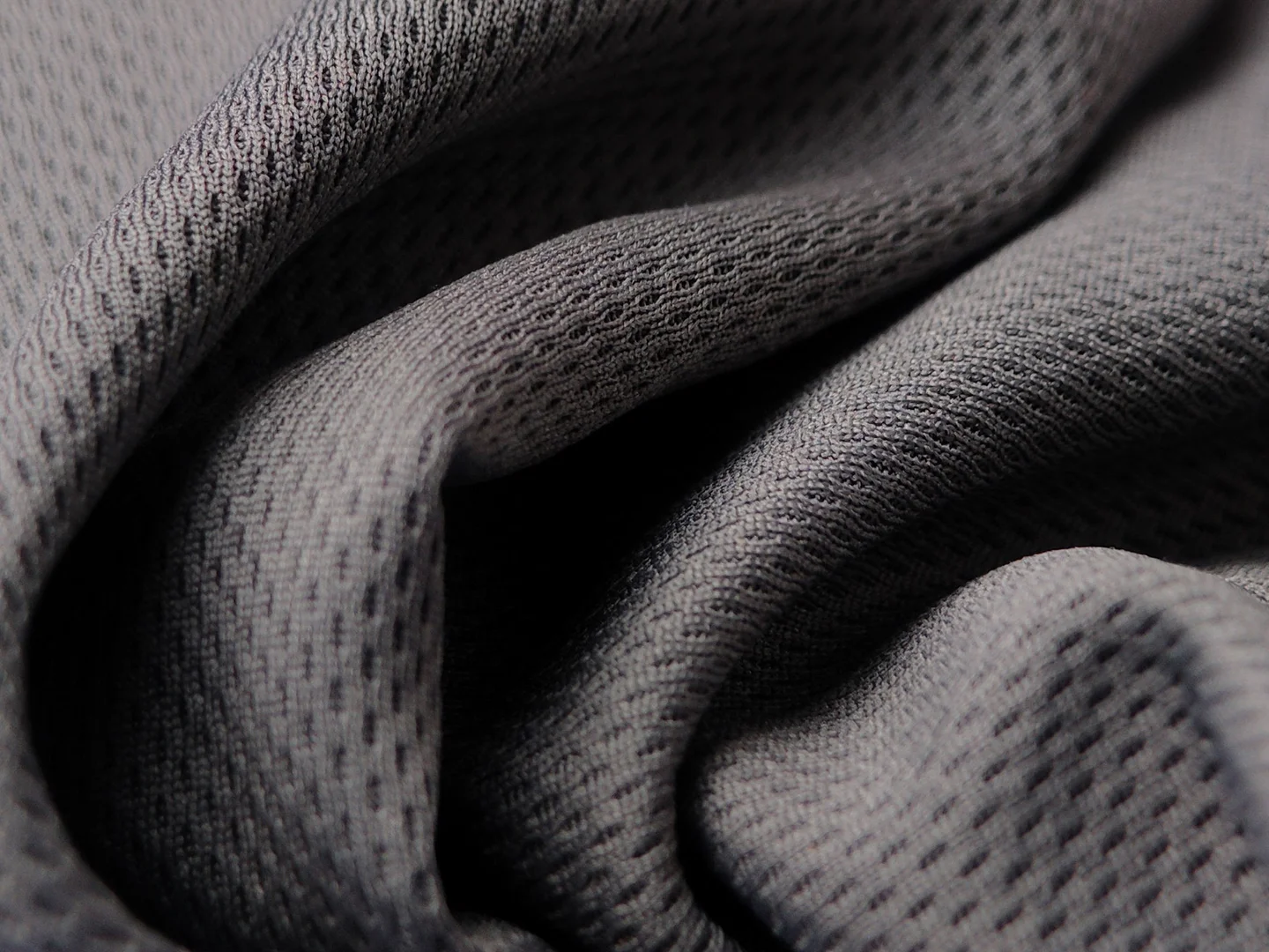 Close-up of gray knitted fabric with visible loops and soft folds