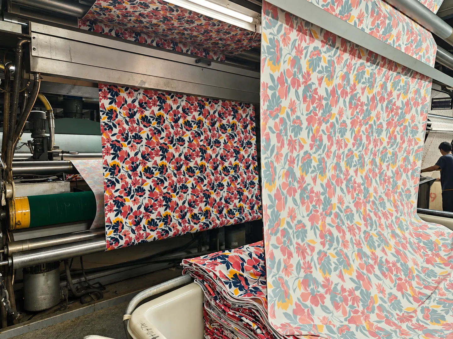 Printed nylon-spandex fabric passing through production machinery in a textile workshop